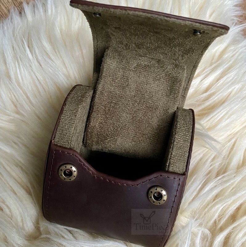 Opened watch case showing velvety inside and M shaped watch cushion half way sliding out.